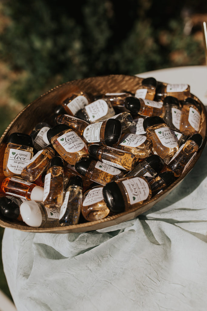 There is a basket of mini hand sanitizers that are for the guests at the wedding party. They each have a sticker saying "spread love, not germs". This is a perfect party favor to have for guests to make sure the wedding adheres to the CDC guidelines. 