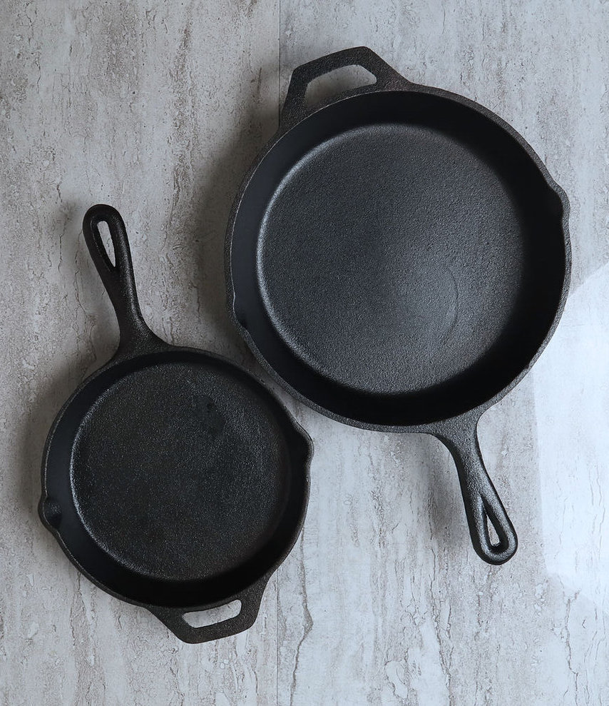 Image of 2 black iron skillets, one bigger than another. One of our recommendations for the wedding gift guide.